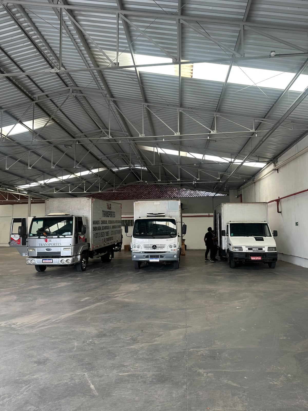 Galpão real da JR Transportes com caminhões e espaço para guarda-móveis em Belo Horizonte
